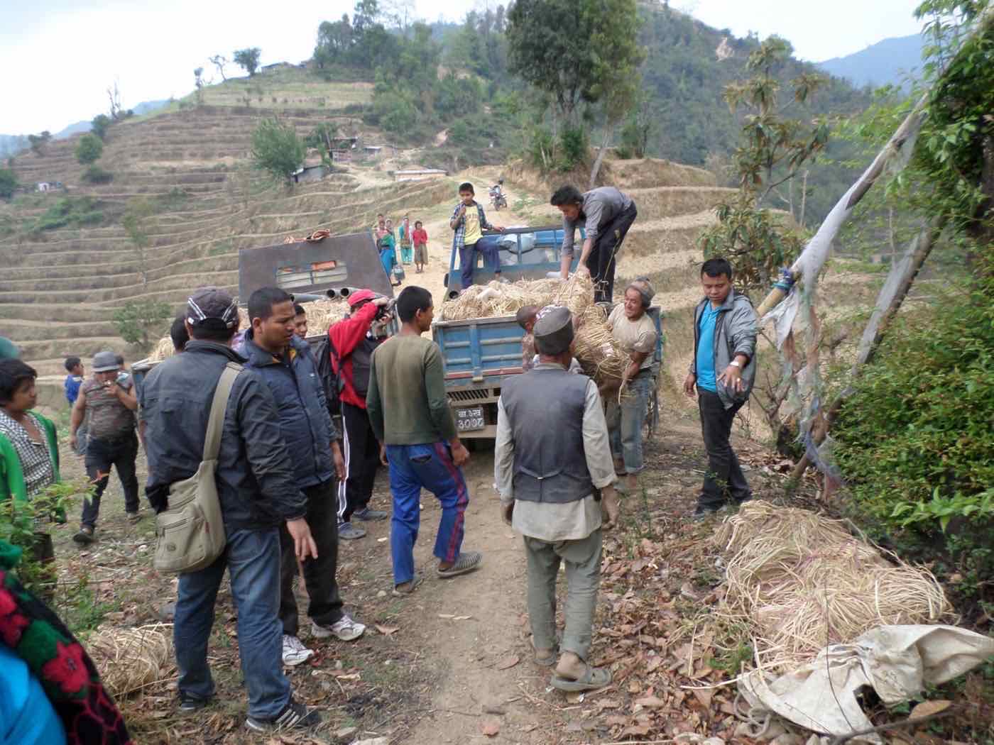 Community members loading harvested farm materials onto a vehicle in the hills of Nuwakot