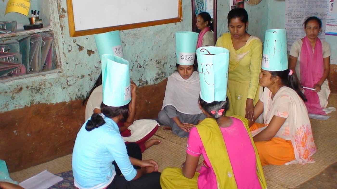 Women in paper hats labelled with group roles, role-playing during a training session
