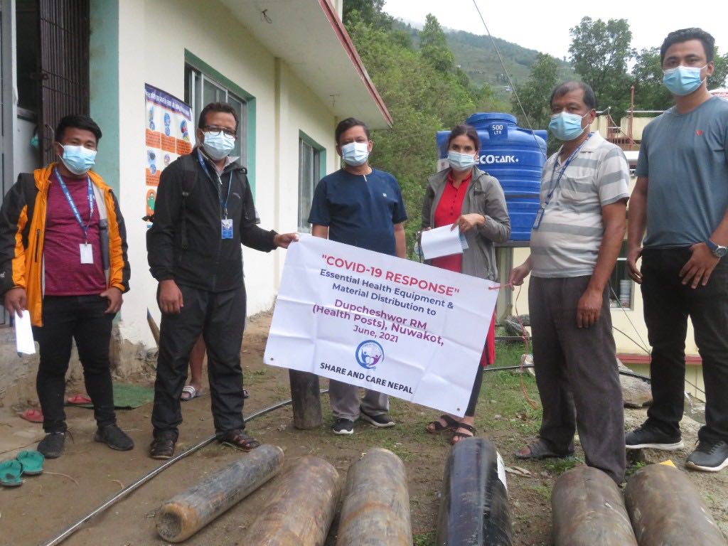 Share and Care Nepal staff with a COVID-19 response banner and oxygen cylinders at a health post in Dupcheshwor, Nuwakot