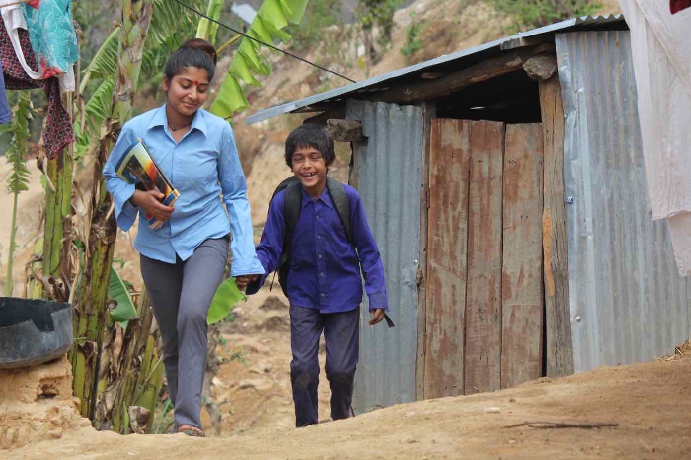 Two children walking hand in hand to school in a Makwanpur village