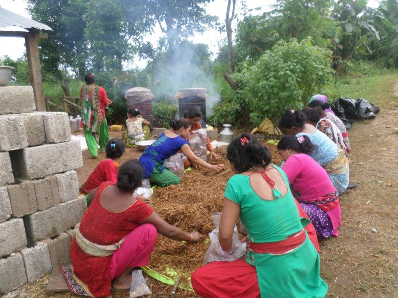 Women working together to pack mushroom substrate bags under a shelter