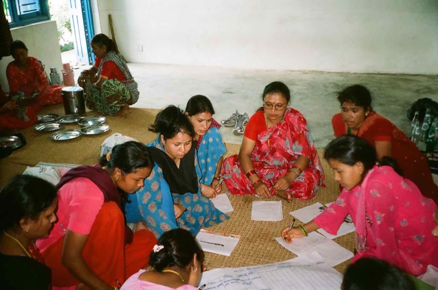 Women working together on papers spread across a floor mat during group work