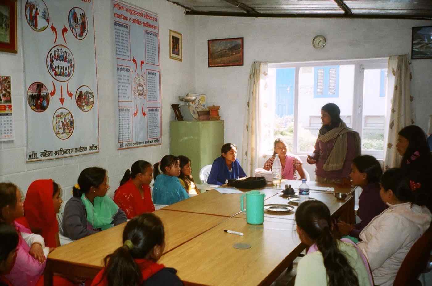 A facilitator leading a session with adolescent girls seated around a table