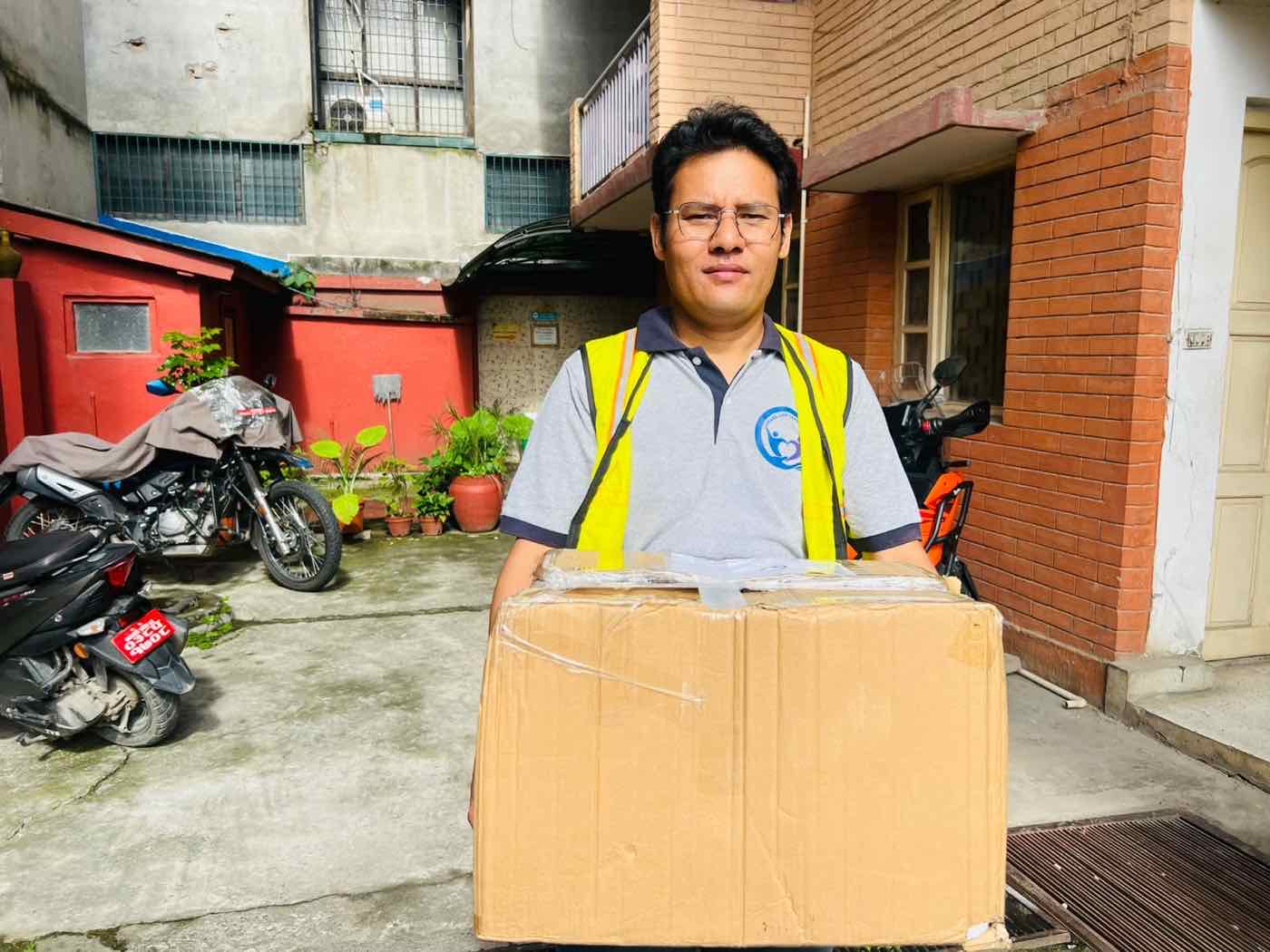 A Share and Care Nepal staff member holding a packed relief parcel ready to be loaded