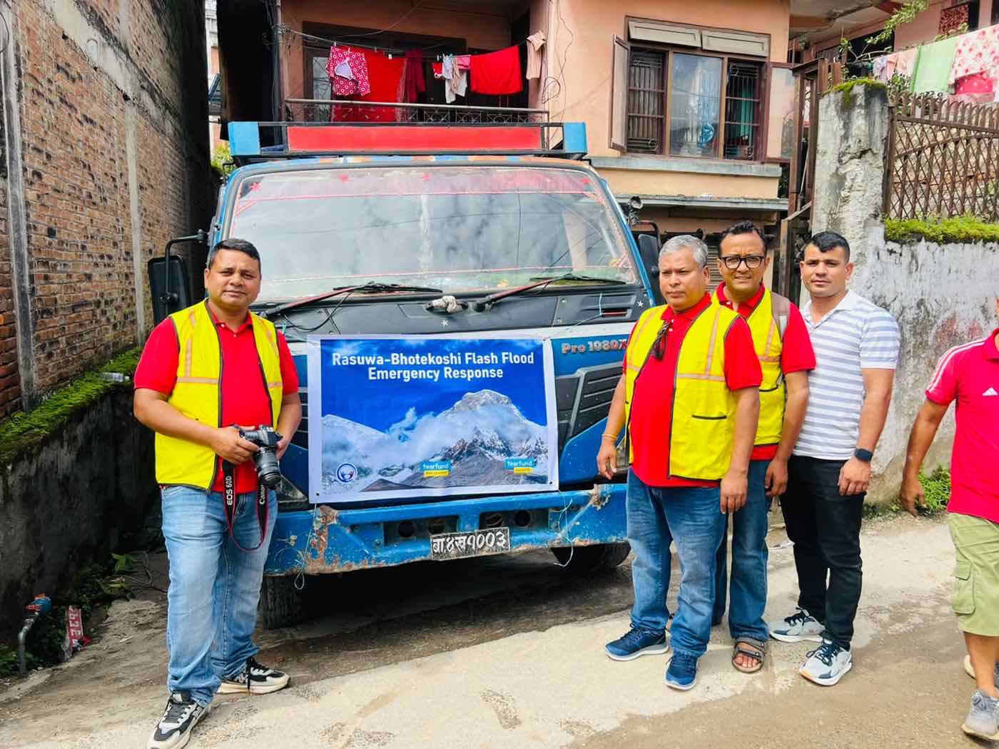 The response team beside a loaded truck carrying a Rasuwa-Bhotekoshi Flash Flood Emergency Response banner with the Tearfund New Zealand and Tearfund Australia logos