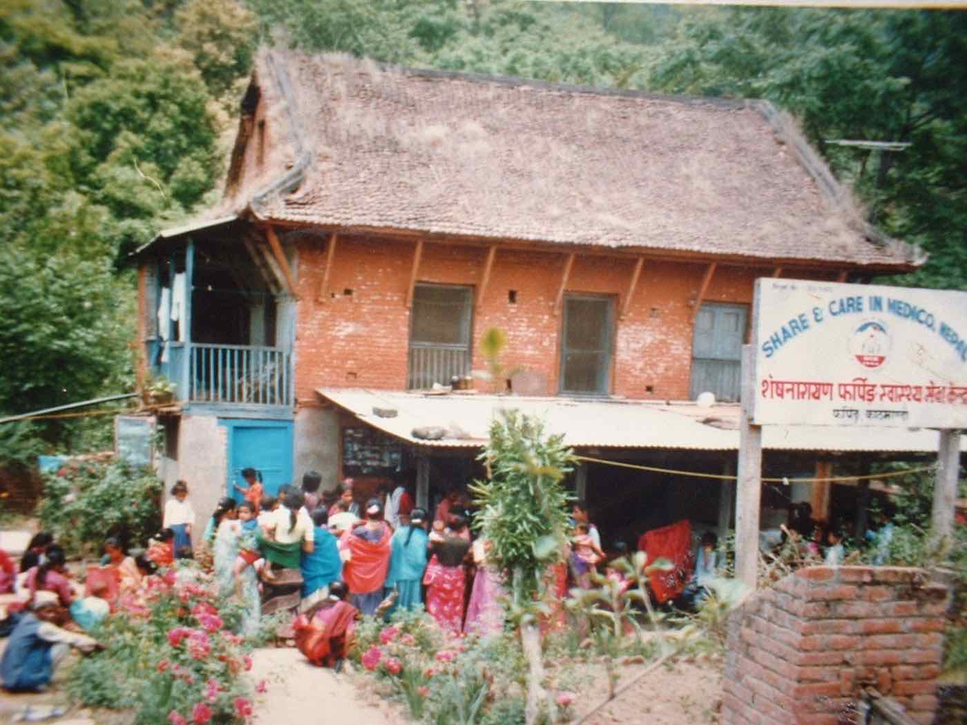 The Share and Care in Medico, Nepal outreach clinic building in Pharping, with community members gathered outside